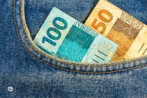 Notas de 100 e 50 reais em bolso de jeans azul